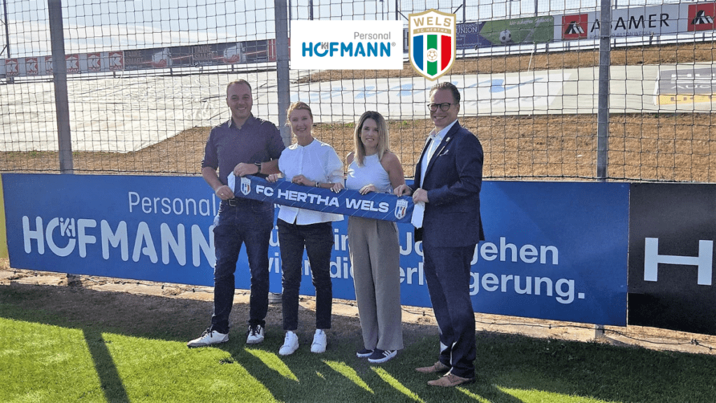FC Hertha Wels: Vier Personen halten Schal vor Hofmann-Werbung in Wels